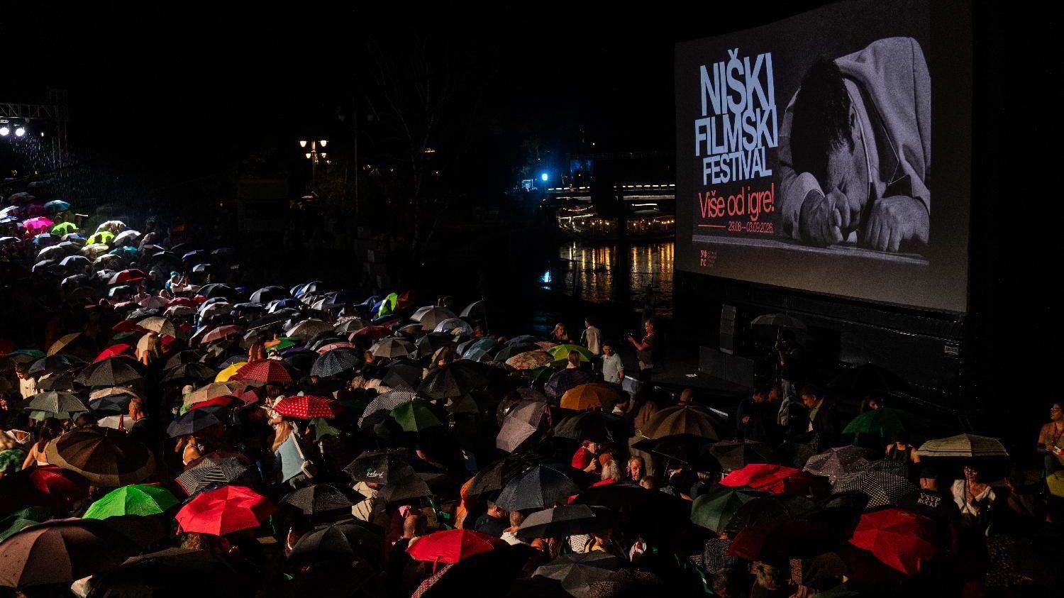 Desetine ljudi sa kišobranima pred binom na kojoj je promo video Niški filmski festival 