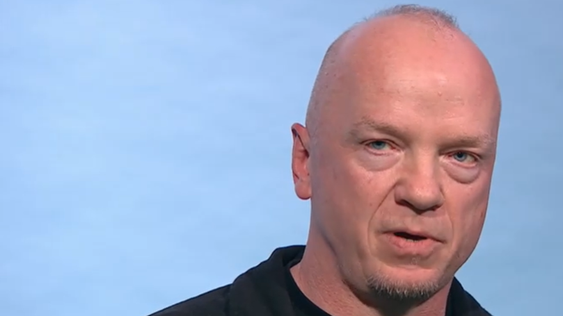 Ćelav muškarac sa kratkom bradom, u crnoj majici, gleda u kameru 