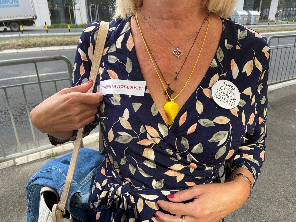 Žena sa bedževima podrške studentima ispred Specijalnog suda