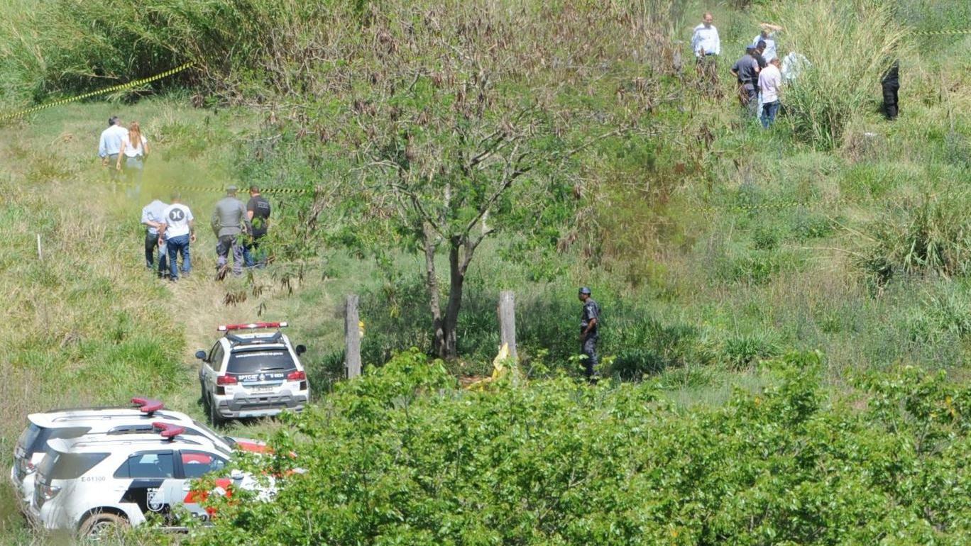 Tri policijska vozila nalaze se na polju okruženom zelenilom i drvećem, dok petoro ljudi stoji u njihovoj blizini.