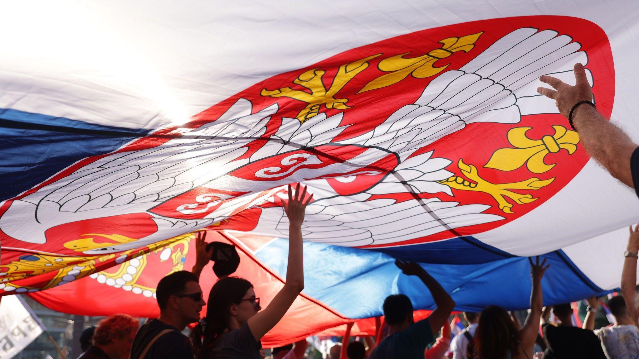 Nekoliko ljudi drži veliku zastavu Srbije