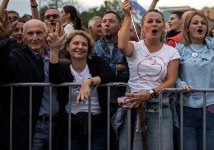 Nekoliko ljudi nasmejano gleda u kameru a prislonjeno je na metalnu ogradu