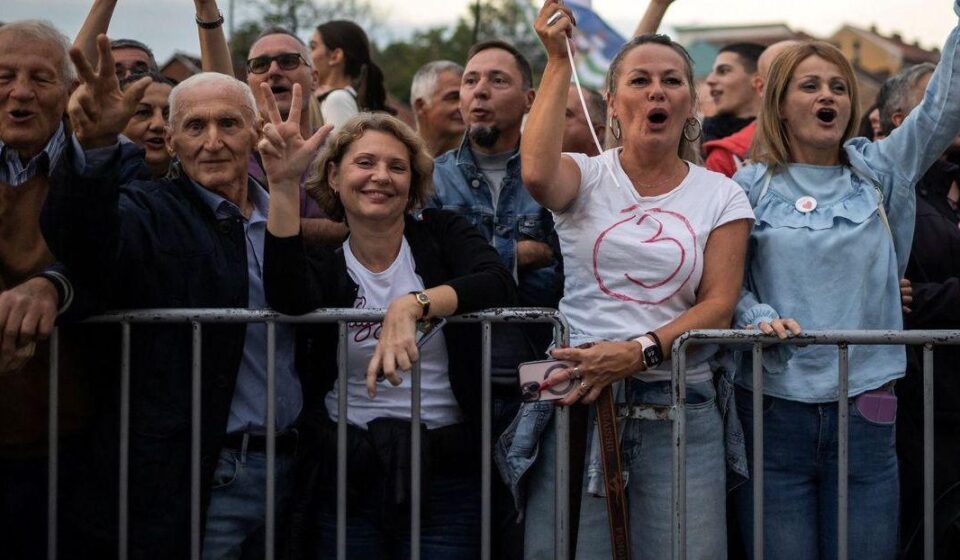 Nekoliko ljudi nasmejano gleda u kameru a prislonjeno je na metalnu ogradu