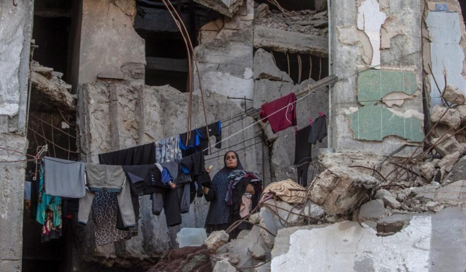 Palestinka skuplja veš koji visi unutar uništene zgrade u gradu Gazi