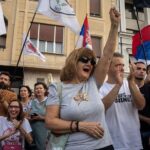 Žena sa podignutom pesnicom u masi na mitingu
