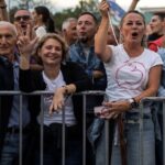 Nekoliko ljudi nasmejano gleda u kameru a prislonjeno je na metalnu ogradu