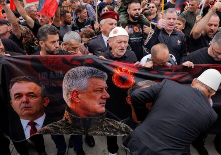 Nekoliko muškaraca drži veliki transparent sa slikom Hašima Tačija u vojničkoj uniformi