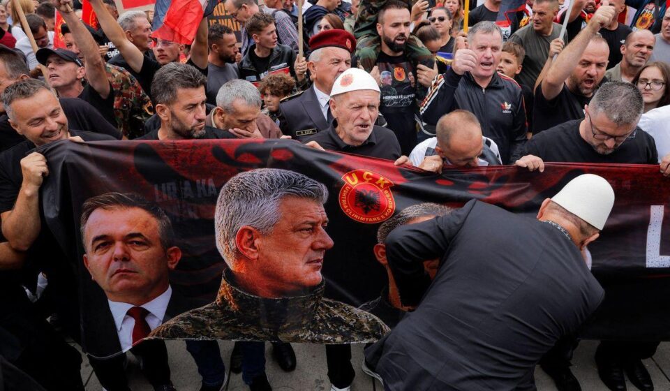 Nekoliko muškaraca drži veliki transparent sa slikom Hašima Tačija u vojničkoj uniformi