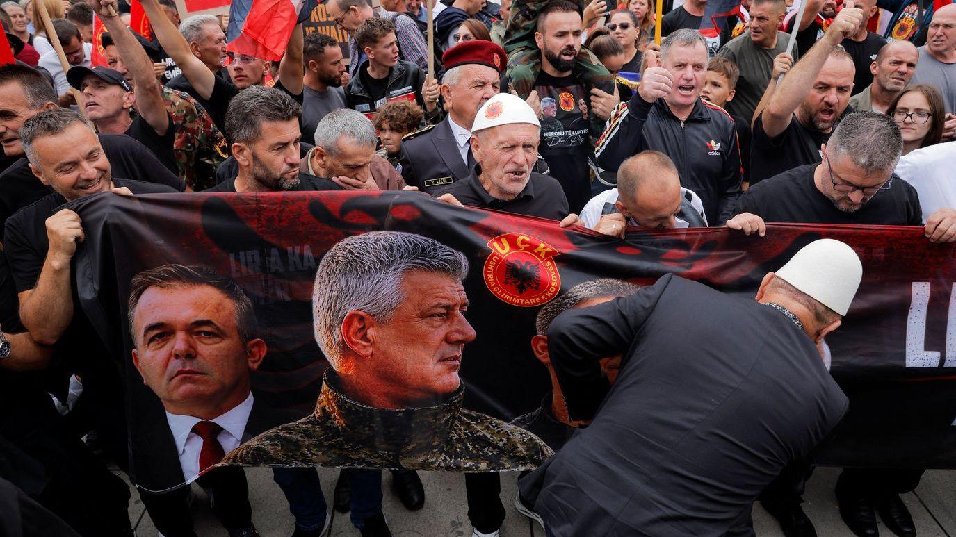 Nekoliko muškaraca drži veliki transparent sa slikom Hašima Tačija u vojničkoj uniformi 