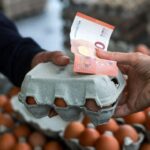 Starija ruka pruža 10 evra i drži korpu sa jajima