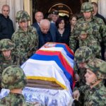 Vojnici nosi kovčeg prekriven zastavama Srbije i Republike Srpske, iza ide žena u crnini, okolo su ljudi