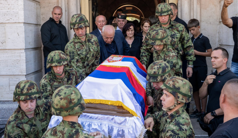 Vojnici nosi kovčeg prekriven zastavama Srbije i Republike Srpske, iza ide žena u crnini, okolo su ljudi