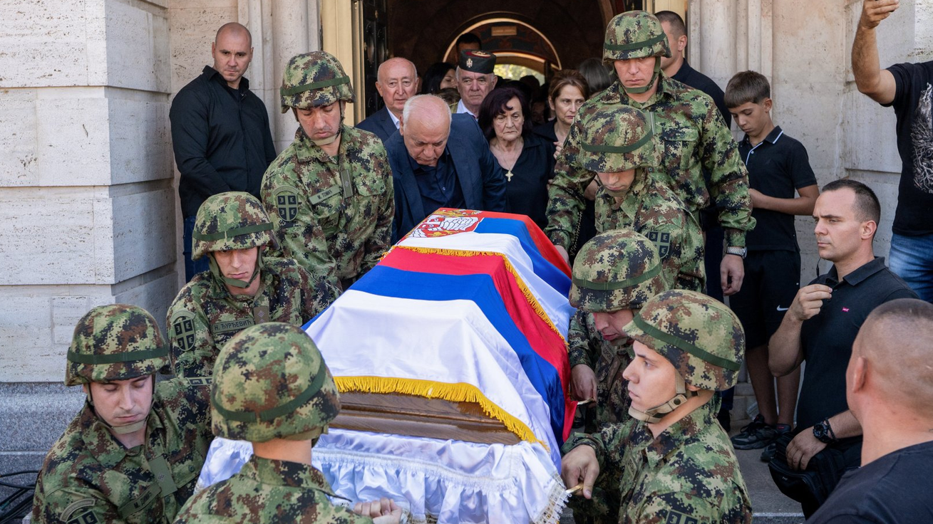 Vojnici nosi kovčeg prekriven zastavama Srbije i Republike Srpske, iza ide žena u crnini, okolo su ljudi