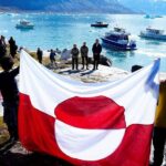 ljudi drže zastavu Grenlanda na obali ostrva