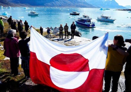 ljudi drže zastavu Grenlanda na obali ostrva