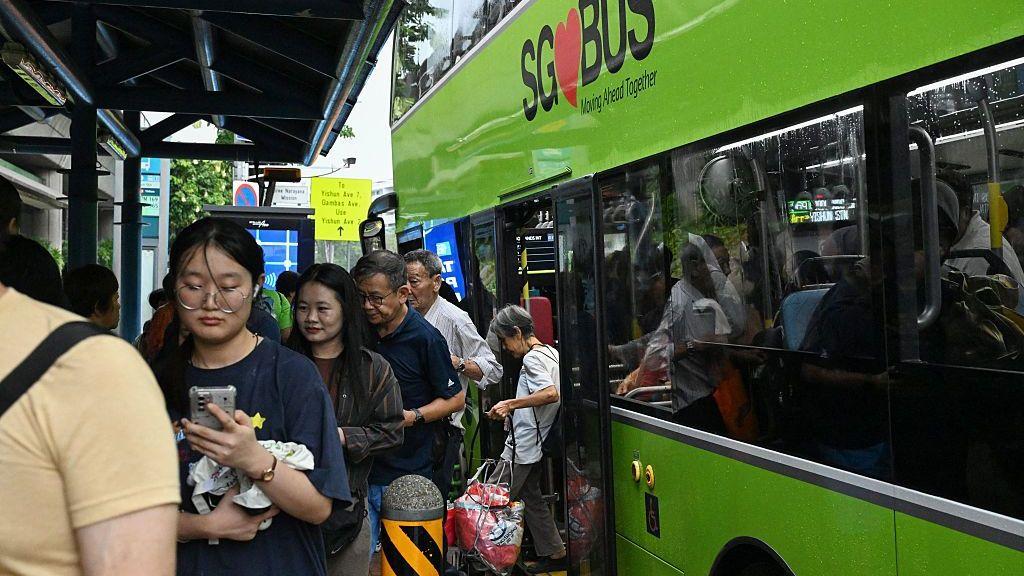 Nekoliko putnika u Singapuru izlazi iz zelenog autobusa