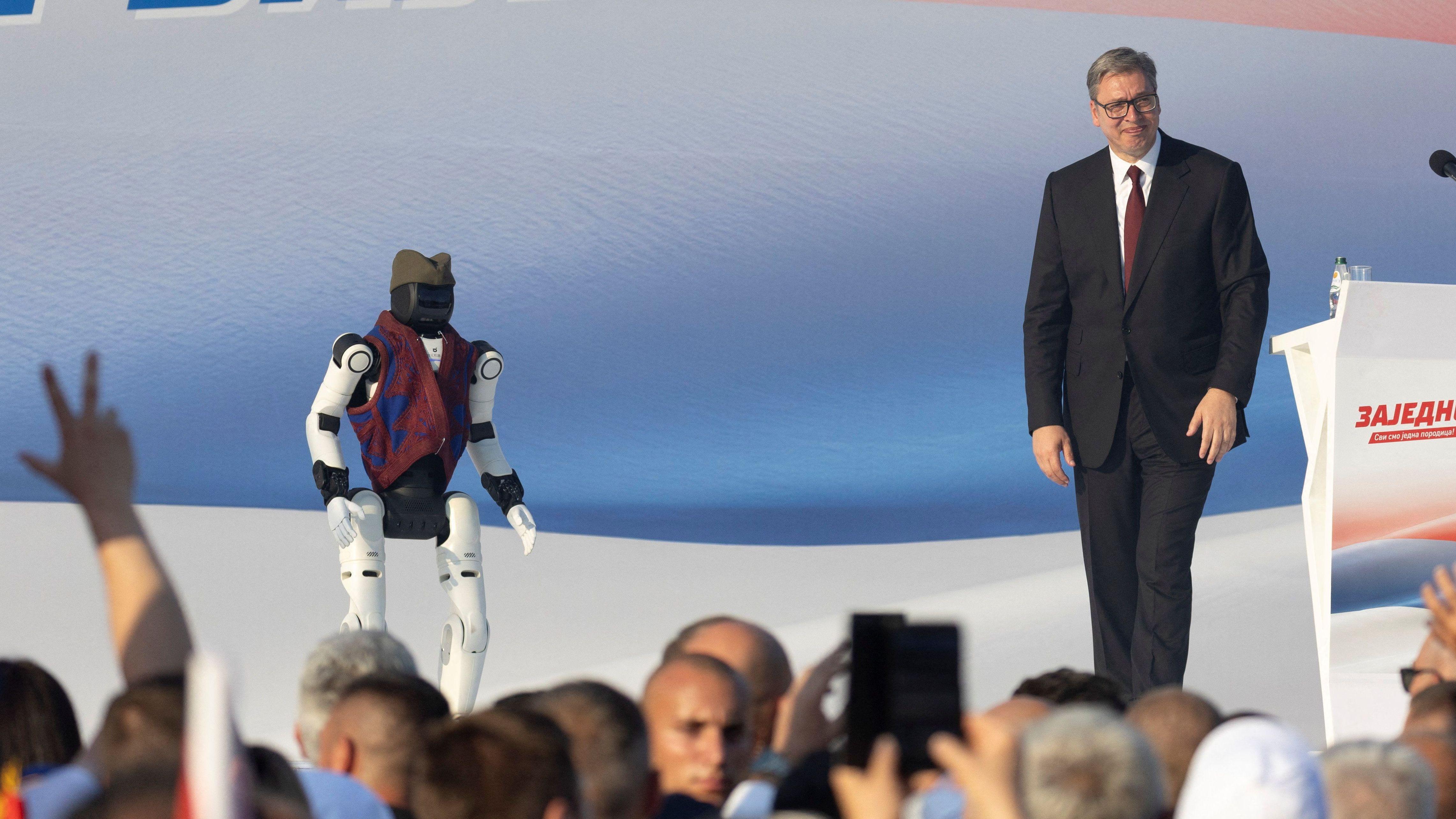 Aleksandar Vučić u odelu i pored njega robot u narodnoj nošnji