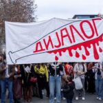 studentski protest sa transparentom na kome je nacrtana bela palica umrljana crvenom krvlju