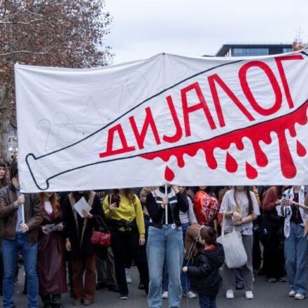 studentski protest sa transparentom na kome je nacrtana bela palica umrljana crvenom krvlju