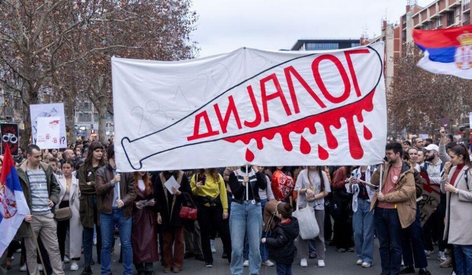 studentski protest sa transparentom na kome je nacrtana bela palica umrljana crvenom krvlju