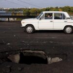Beli automobil prolazi pored rupe na betonskom kolovozu mosta Pivnični, koji je pogođen ruskim dronom.