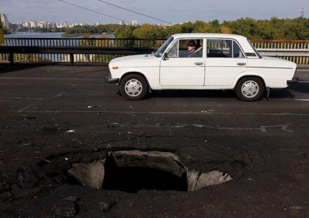 Beli automobil prolazi pored rupe na betonskom kolovozu mosta Pivnični, koji je pogođen ruskim dronom.