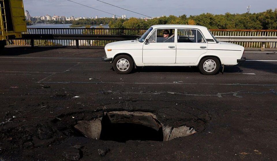 Beli automobil prolazi pored rupe na betonskom kolovozu mosta Pivnični, koji je pogođen ruskim dronom.