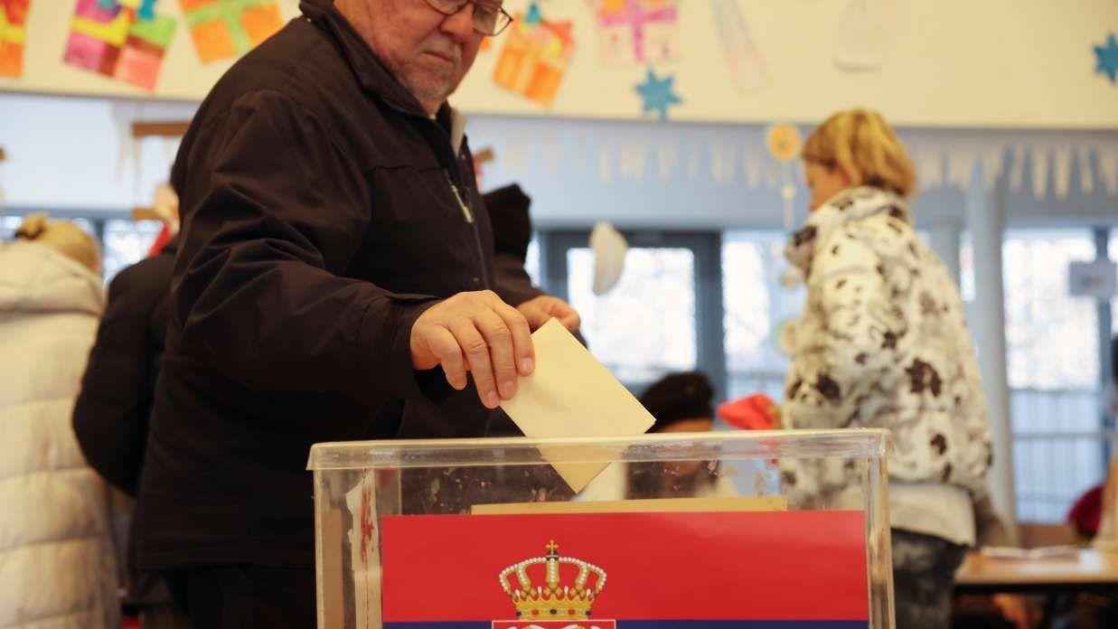 Stariji čovek ubacuje listić u glasačku kutiju