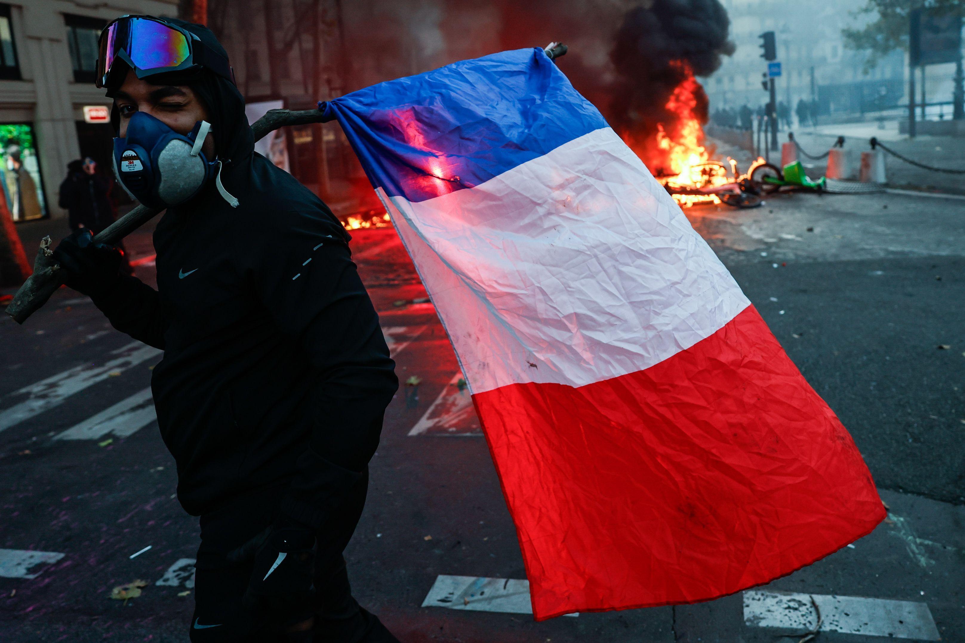 Demonstrant drži zastavu, vatra iza njega
