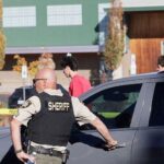 dvojica američkih policajaca stoje pored automobila ispred škole