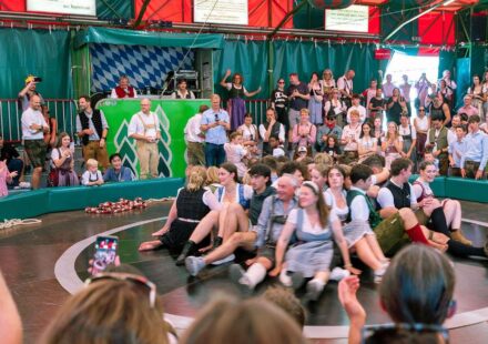 Žene sede u krugu, oko njih ljudi u Minhenu na Oktoberfestu