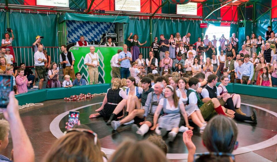Žene sede u krugu, oko njih ljudi u Minhenu na Oktoberfestu