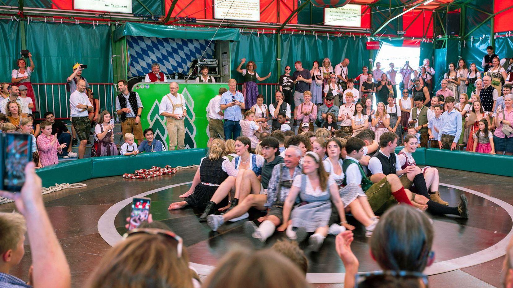 Žene sede u krugu, oko njih ljudi u Minhenu na Oktoberfestu